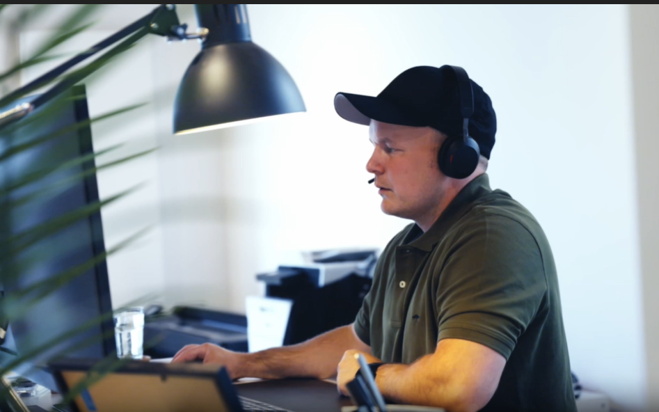 Simon Rausch sitzt an seinem Schreibtisch am Computer, eine Schreibtischlampe im Vordergrund.